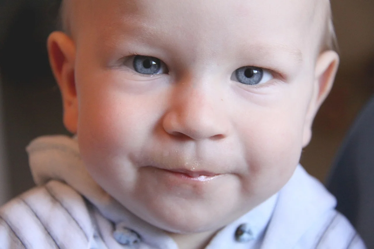 Bild eines kleinen Jungen der in die Kamera blickt.